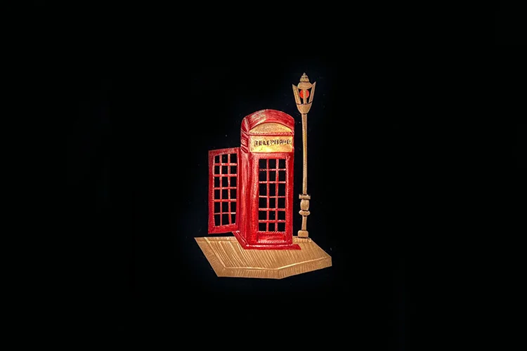 Red British telephone booth relief artwork with street lamp on a wooden base