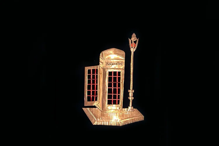 Gold British telephone booth relief artwork with street lamp on a wooden base